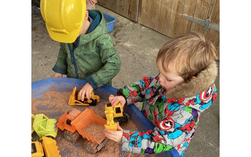 Children playing with sand and trucks