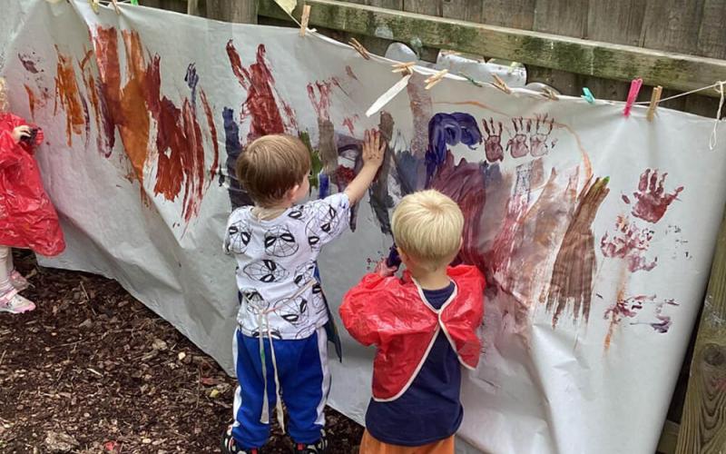 Children apinting on a huge sheet outside