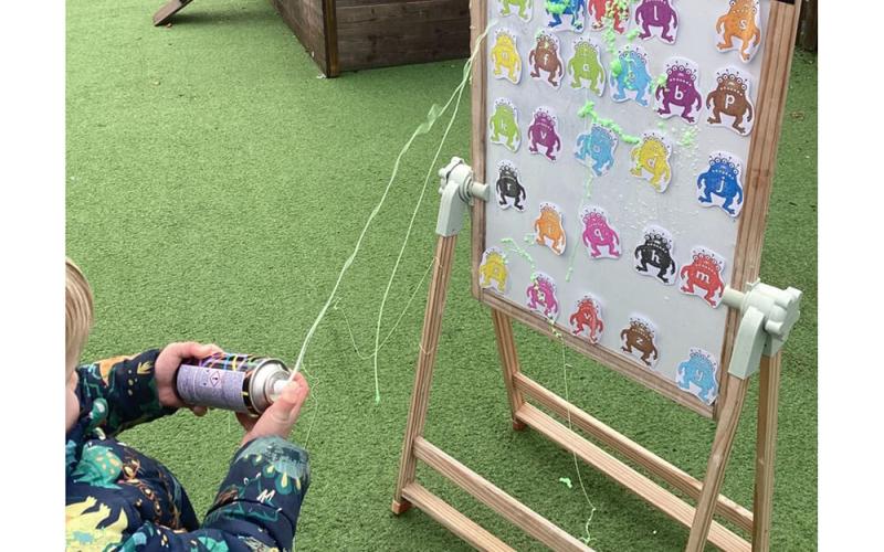 Child squirting foam at figures of aliens with letters on