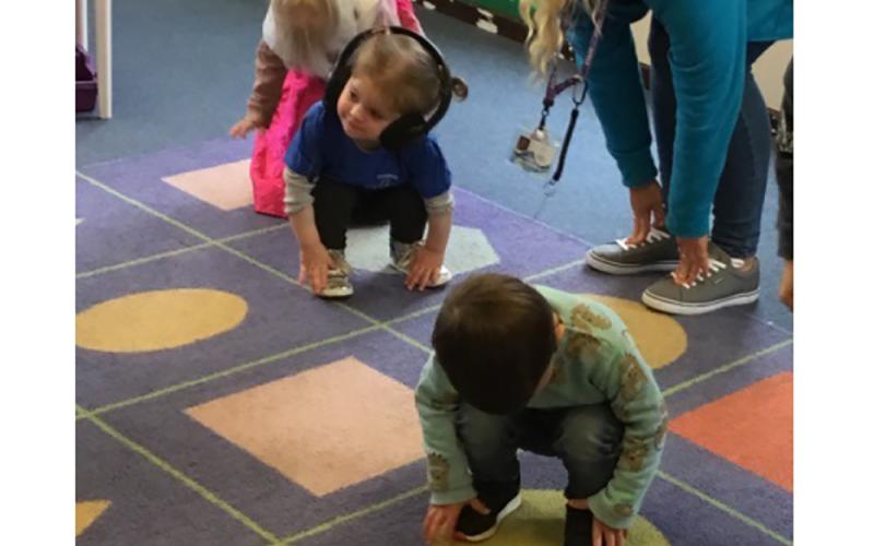 Children playing on shapes in a carpet